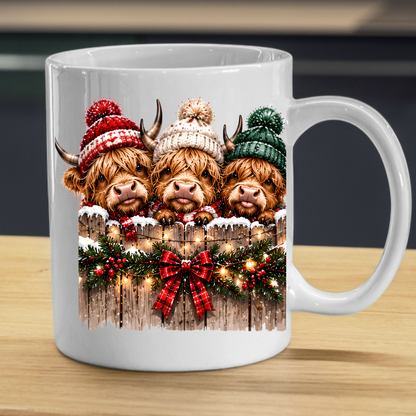 Highland Cows Christmas Fence Mug "Merry & Bright" Festive Highland Cows 325ml Ceramic Coffee Mug – Three Cute Cows in Winter Bobble Hats Behind Snowy Fence with Fairy Lights & Red Tartan Bow | Christmas Gift | Fast Dispatch by UK Seller (M3429)
