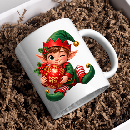 Christmas Mug "Winking Christmas Boy Elf Red Bauble" Winking Christmas Boy Elf 325ml Ceramic Coffee Mug – Cute Festive Tea Cup with Elf Outfit Jingle Bells Snowflake Bauble Graphic Gift | Available in Multicolours | Fast Dispatch by UK Seller (M3186)